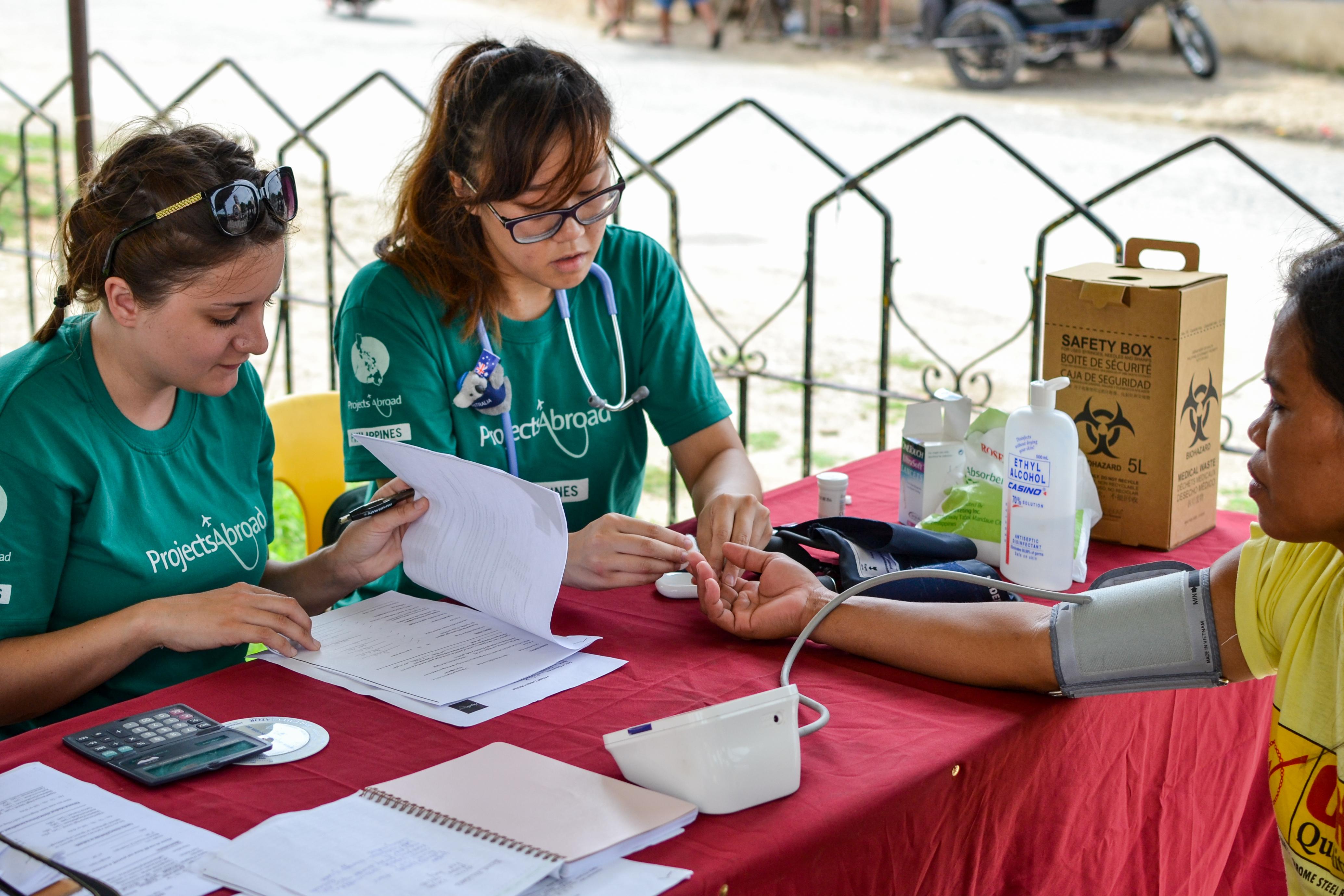 On the Public Health Group Internship in the Philippines, interns check the vital signs of people during an outreach. As part of the Projects Abroad Public Health group work in the Philippines, interns check the blood pressure of patents.